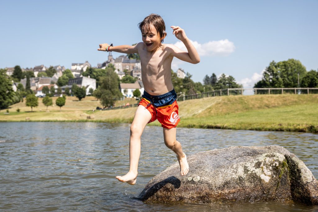 Kind dat van een rots springt bij het Lac de la Tour d'Auvergne